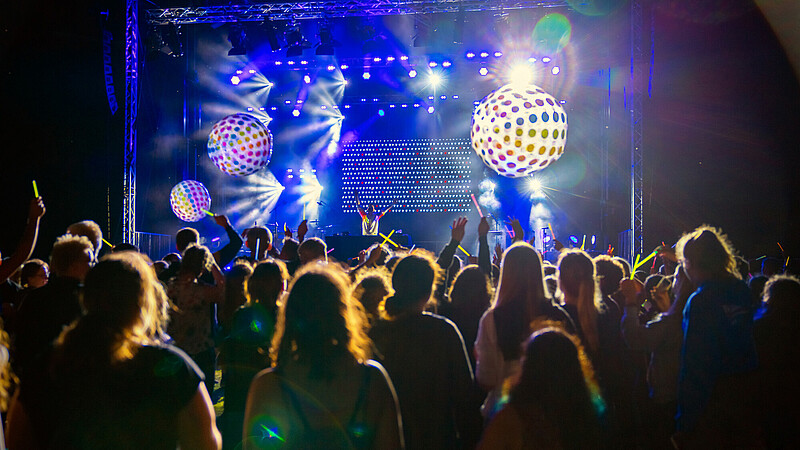 Junge Menschen tanzen auf einem Konzert vor der Bühne